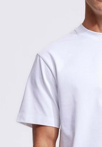 Witte katoenen t-shirt met korte mouwen, een ronde hals en een gladde textuur. De stof lijkt lichtgewicht en eenvoudig.