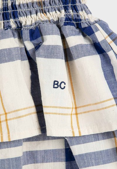 Tissu à carreaux bleu, blanc et jaune avec une ceinture froncée et des lettres brodées "BC" près de l'ouverture d'une poche.