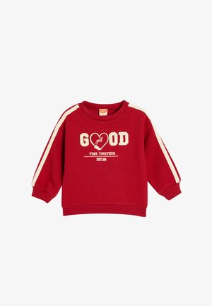Sudadera roja con rayas crema en las mangas. Presenta un texto difuso que dice "BUEN tiempo de GOLF JUNTOS" y una fecha establecida. Puños y bajo acanalados.