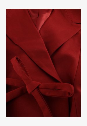 Red wrap-style coat featuring a textured fabric, wide lapels, and a matching waist tie. The interior is lined with a smooth fabric.