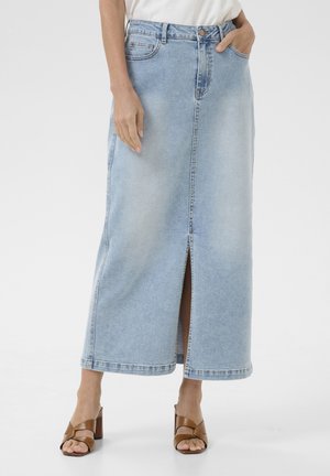 Light blue denim maxi skirt with a front slit, classic five-pocket design, and a fitted waist, paired with brown heeled sandals.