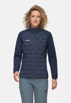 Marineblauwe geïsoleerde jas met een gequilt Vorderzijde, gladde mouwen, opstaande kraag en ritszakken. Minimale branding is zichtbaar.