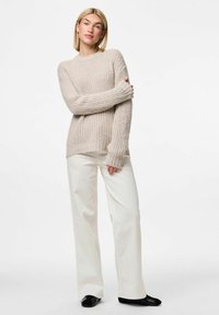 Lichtbeige gebreide trui met ribbeltextuur en lange mouwen, gecombineerd met witte wijde broek en zwarte schoenen. Eenvoudig en casual ontwerp.