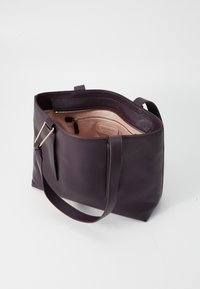 Purple leather tote bag with a structured shape, featuring a smooth exterior, dual handles, and a light-colored interior with a zip pocket.
