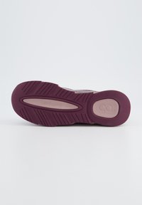 Semelle de chaussure en caoutchouc violet texturé ; présente un logo circulaire et des motifs striés pour l'adhérence ; zone centrale lisse.