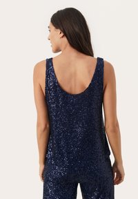 Marineblaue Top mit Pailletten und Rundrücken-Design. Der Stoff ist mit glänzenden, reflektierenden Pailletten bedeckt, die die gesamte Oberfläche verzieren.