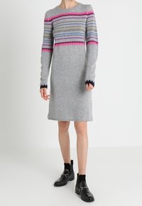 Graues Strickkleid mit langen Ärmeln, mehrfarbigen Zickzackmustern in Pink, Blau und Marineblau, mit einem runden Ausschnitt und Saum.