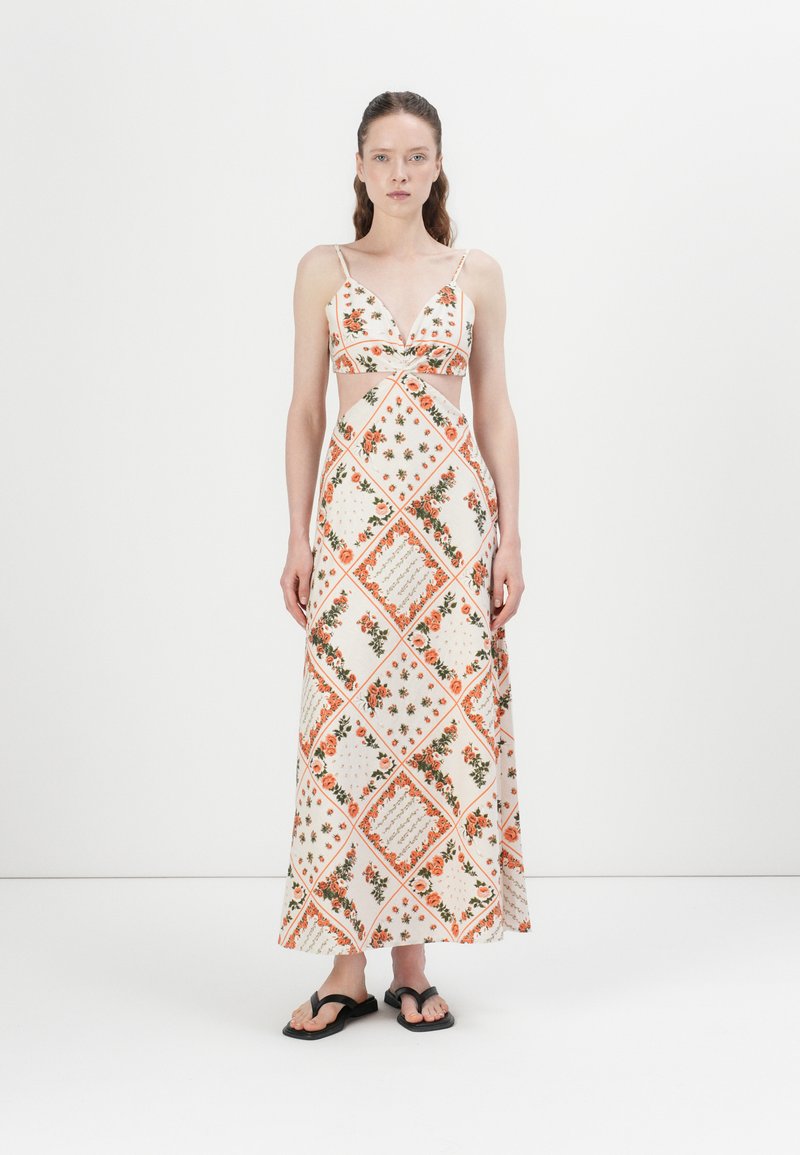 Maxi-jurk met een diagonaal bloemenpatroon in oranje en groen op een crèmekleurige achtergrond, met een uitsnijdesign en dunne verstelbare bandjes.