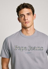 Šedé bavlněné tričko s nápisy "Pepe Jeans" a "London" v kontrastní modré a stříbrné barvě, krátké rukávy, kulatý výstřih.
