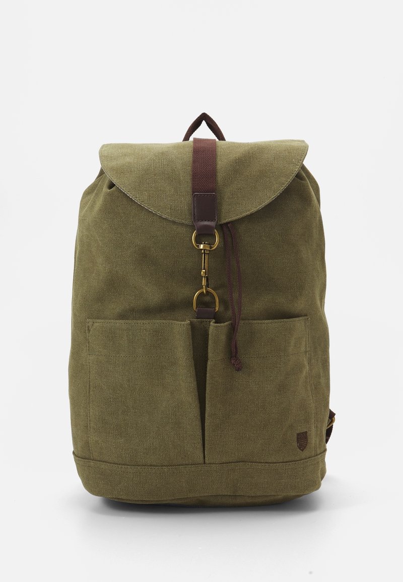 Sac à dos en toile vert olive avec un rabat repliable, une sangle en cuir marron et des accents, deux poches avant et une finition texturée.