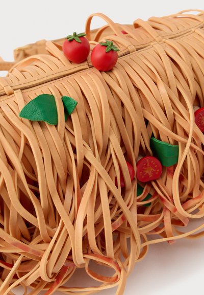 Tan spalvota spageti formos rankinė, pagaminta iš guminės medžiagos, papuošta mažomis raudonomis pomidorų akcentais ir žaliais lapų detalėmis. Uždarymas užtrauktuku viršuje.