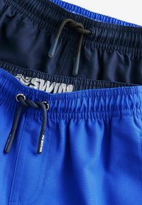 Shorts de bain bleus avec une taille élastique, dotés d'un cordon de serrage noir. Tissu lisse, couche supérieure en bleu marine foncé, couche inférieure en bleu vif.