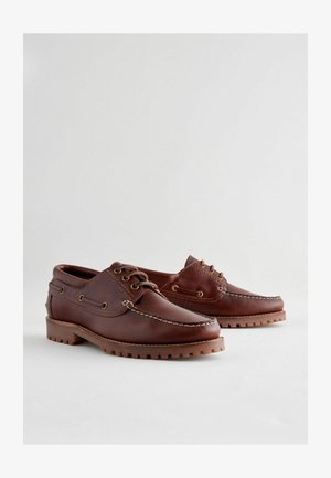 Ruske nahkasaappaat, joissa on pyöreä kärki, nauhakoristelu, kontrastiväriset ompeleet ja kumipohjat, joissa on teksturoitu pintakuvio.