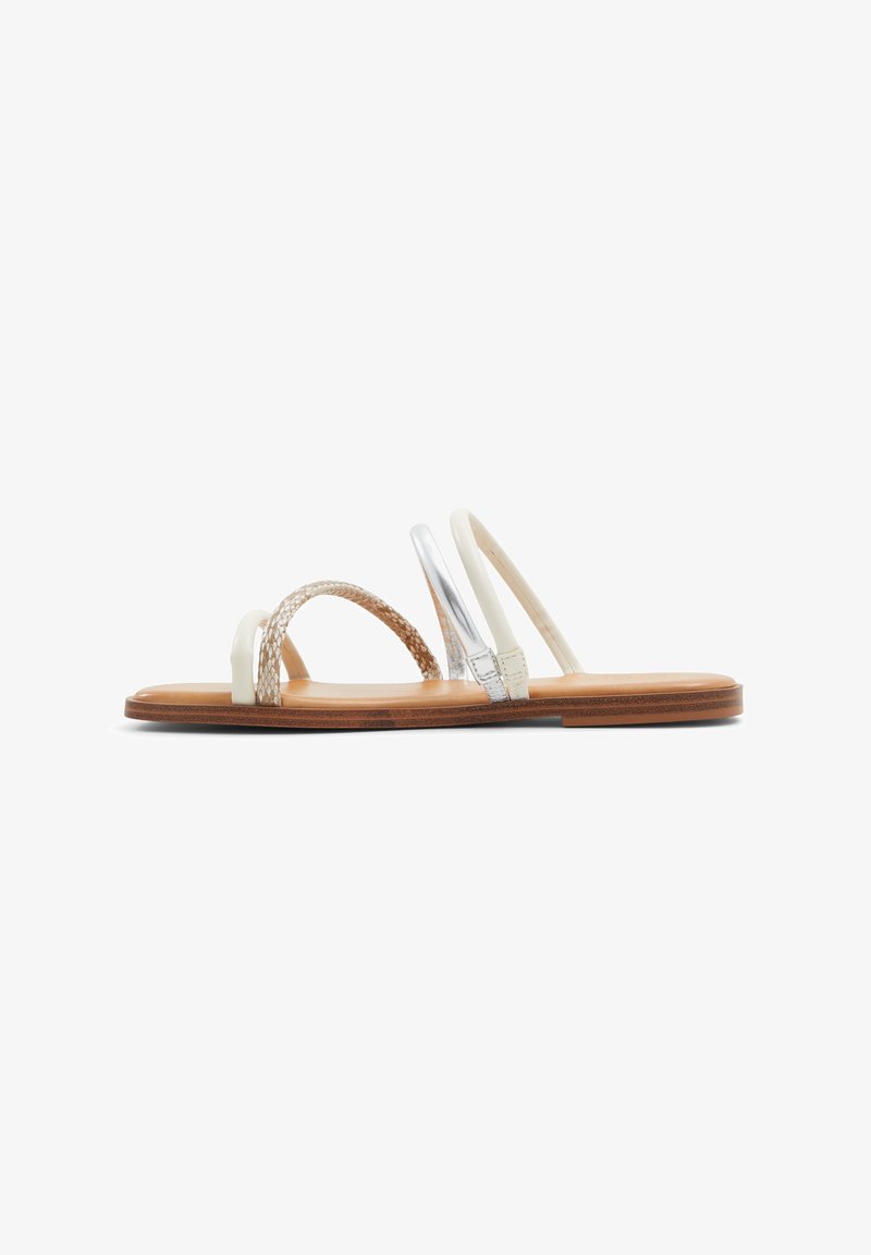 Płaskie sandały z brązową drewnianą podeszwą, białymi paskami, plecionym akcentem oraz błyszczącym srebrnym detalem na jednym pasku. Gładka tekstura na całej powierzchni.