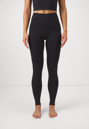 Leggings de tiro alto en negro, confeccionados con una tela elástica, que presentan una textura suave, un diseño ajustado al cuerpo y sin marcas ni patrones visibles.