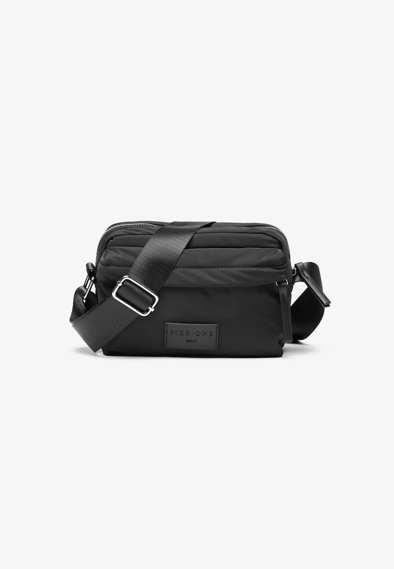 Borsa a tracolla nera in nylon resistente, con finitura testurizzata, chiusura con zip, tracolla regolabile e logo in rilievo su una patch quadrata.