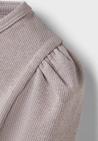 Bleg lilac, ribbet strikstof med samlede puffærmer og en struktureret halsudskæring. Blød tekstur med subtil glansdetalje.