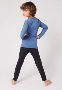 Maglietta a maniche lunghe blu realizzata in materiale morbido con scollatura rotonda, abbinata a leggings neri aderenti. Design semplice, senza motivi o grafiche visibili.