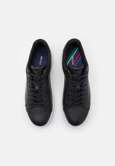 Black leather sneakers with round toes, lace-up design, and white rubber soles. Interior features a multicolored striped insole.