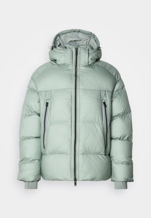 Prešívaná bunda svetlo mätovej farby s vysokým golierom, predným zipsom a dvoma bočnými vreckami so čiernymi zipsami a elastickými manžetami.