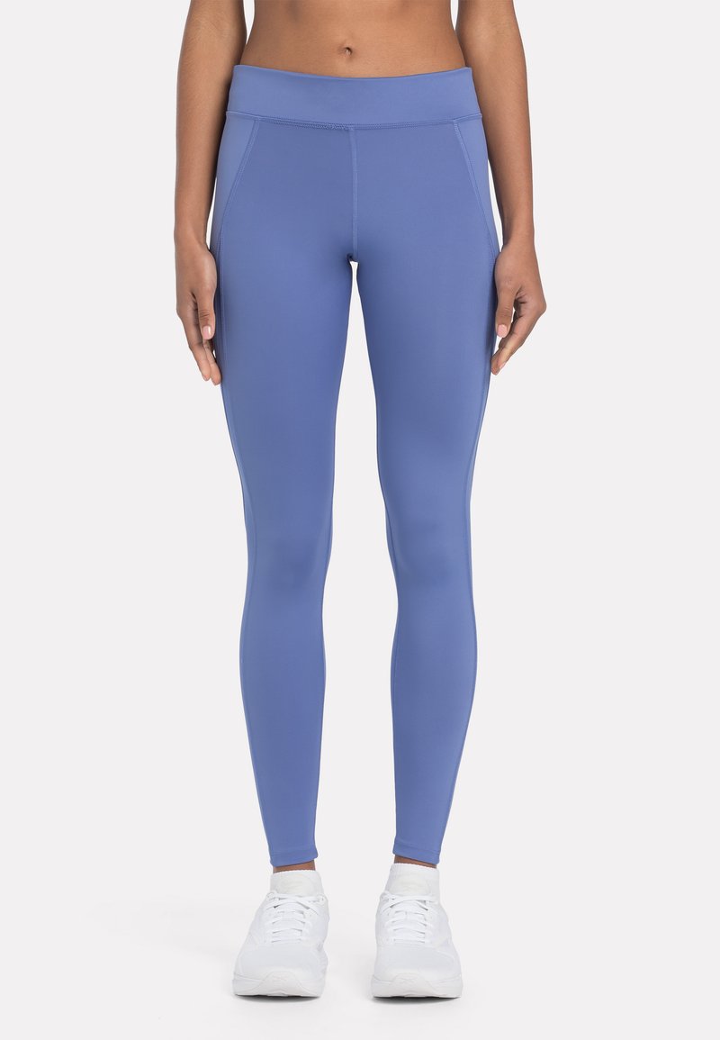 Leggings de tiro alto, ajustados al cuerpo, en un suave material azul claro con una textura lisa y un sutil detalle en las costuras, combinados con zapatillas blancas.