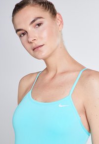 A light blue athletic tank top with thin straps and a rounded neckline, featuring a small white Nike logo on the chest area.
