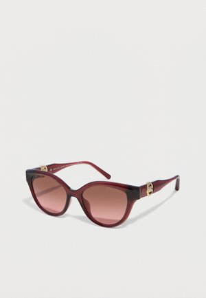 Cat-eye burgundy sunglasses with gradient brown lenses and gold logo accents on the temples against a white background.