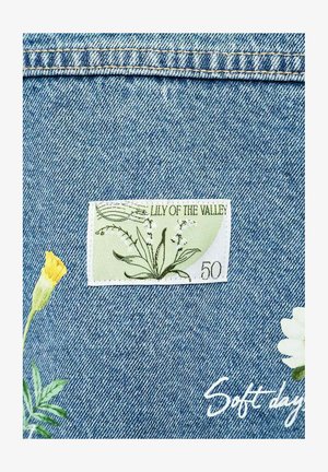 Tkanina dżinsowa z naszywką "Konwalia majowa", kwiatową haftem w żółtym i białym kolorze oraz białym kursywnym napisem "Miękkie dni."