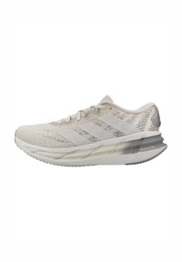 Chaussure de course Adidas beige clair avec tige texturée, trois bandes sur le côté, semelle rembourrée et texte "Repetition" sur le talon.