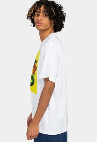 White cotton t-shirt featuring a colorful snake and leopard graphic on a yellow background. Short sleeves and relaxed fit design.