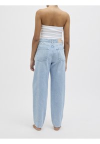 Světlé modré džíny s vysokým pasem a volným střihem, s dvěma zadními kapsami a viditelnou značkou na pasu.