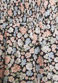Blumenkleid mit schwarzem Hintergrund und kleinen rosa, weißen und blauen Blumen. Das Oberteil hat geraffte Falten für Textur.