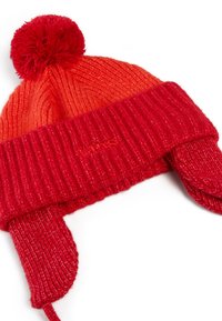 Czerwona, pleciona czapka beanie z pomponem, z prążkowanym mankietem i uszami. Tekstura jest miękka i ma lekkie połysku.