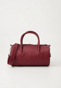 Sac à main en cuir bordeaux de forme arrondie, avec un logo embossé, deux anses et une bandoulière amovible. Surface texturée avec des éléments métalliques.