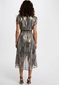 Robe semi-transparente, longueur genoux, au motif serpent, avec des manches courtes volantées et une taille smockée dans des tons de gris et beige.