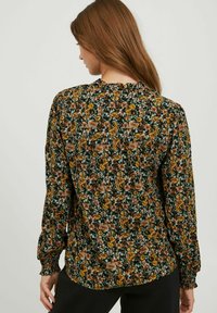 Blumenbluse mit schwarzem Hintergrund, verziert mit kleinen braunen und gelben Blumen, mit Raffung an den Ärmeln und einer lockeren Passform. Leichtes Material.