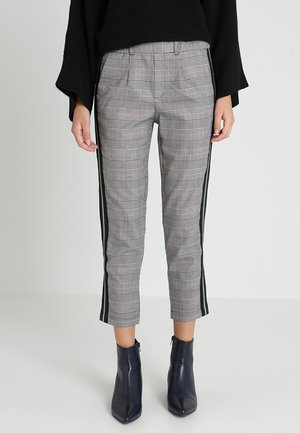 Rutet ankel-lange bukser med sorte sidelister, båret med sorte ankelstøvler med spids tå og en sort langærmet top.