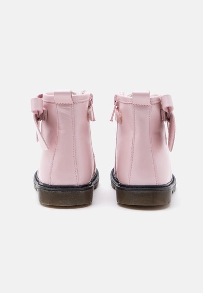 Paire de bottines en cuir rose avec semelles noires et languettes arrière, vues de dos sur fond blanc.