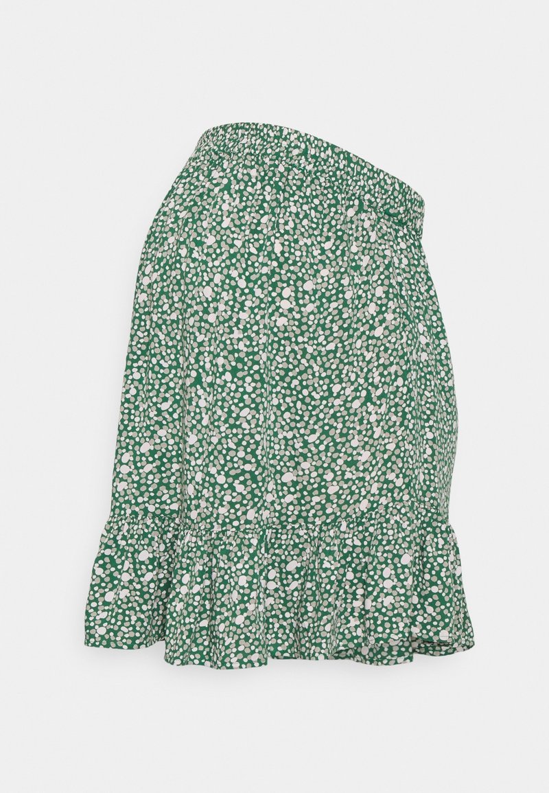 Jupe verte avec motif de pois blancs dispersés, taille élastique et ourlet à volants, présentée à plat sur fond blanc.