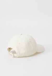 Cappellino da baseball in cotone color avorio, con visiera curvata, cinturino regolabile sul retro e sei fori di ventilazione.