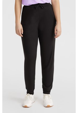 Zwarte sweatpants met een elastische tailleband en trekkoord, met een taps toelopende pootontwerp en een zachte textuur, gecombineerd met witte sneakers.