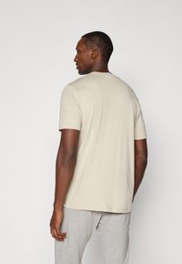 Beige kortærmet T-shirt med rund halsudskæring og opsmøgede ærmer. Glat tekstur, afslappet pasform og enkelt design uden mønstre.