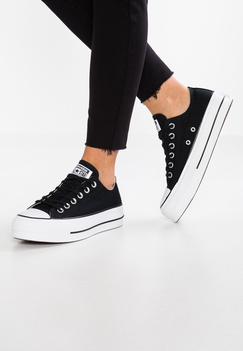 Schwarze Leinenschuhe mit niedrigem Schnitt, weißer Gummisohle, schwarzen Schn�ürsenkeln und einer kontrastierenden weißen Zehenkappe.
