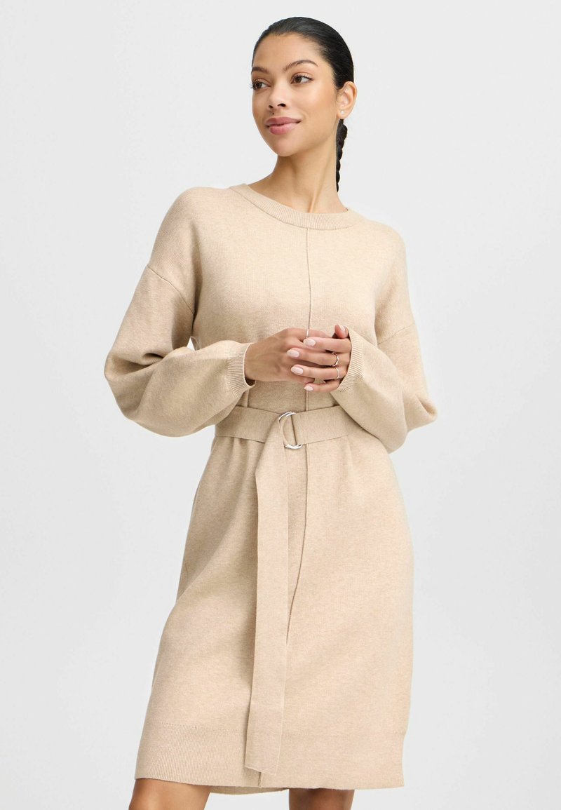 Beige Strickkleid mit langen, übergroßen Ärmeln, einem runden Ausschnitt und einer taillierten, mit einer Metallverschluss-Akzent versehenen Taille. Weiche Textur.