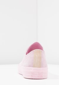 Sneaker slip-on in suede rosa con una patch beige sul tallone e una suola in gomma testurizzata con branding in rilievo.