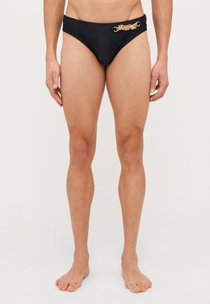 Slip da bagno neri realizzati in tessuto liscio, con un dettaglio del logo dorato sulla cintura. Progettati per un look aderente e con copertura minima.