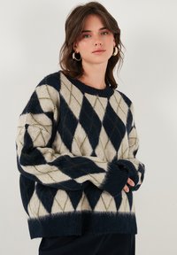 Maglione misto lana con motivo a rombi in blu navy, crema e verde muschio. Linea oversize con scollatura tonda e polsini a coste.