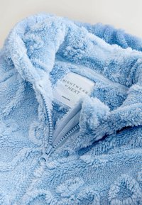 Svetlomodré nadýchané nočné oblečenie na zips s textúrovaným vzorom, vyrobené z mäkkej látky a s etikietou "NIGHTWEAR by NEXT".