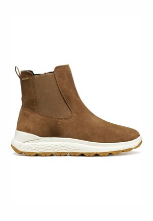 Bottines en suede marron à enfilage, avec des panneaux latéraux élastiques, semelle blanche rembourrée et semelle extérieure en caoutchouc texturé.