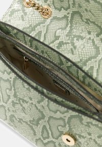 Zielona torebka o fakturze z wzorem wężowej skóry, złote okucia, łańcuszkowy akcent oraz kieszeń zapinana na suwak wewnątrz.